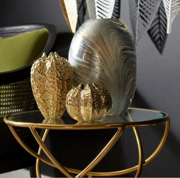 This abstract accent vase features a hammered metal form, coated in a shimmering gold finish. Perfect for any tabletop ensemble with ambitious elegance as the foundation for style and design. Store your floral arrangements in this vessel to display in your home office, bathroom, living room, or bedroom. This vase is also great for commercial or hospitality applications for added luxury in common areas and lobbies.  Dimensions: H 7.25 x Diameter 5